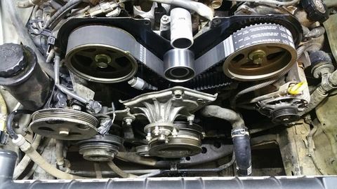 Close-up of a new timing belt on the cam gears with the water pump exposed
